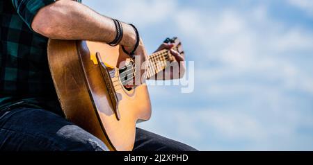 Akustische Gitarren spielen. Musikkonzept. Gitarren akustisch. Männlicher Musiker, der Gitarre spielt, Musikinstrument. Die Hände des Mannes spielen akustische Gitarre, nahe Stockfoto