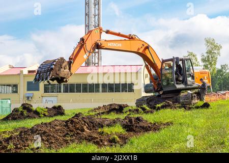 Kemerowo, Russland - 29. juni 2021 werden Erdarbeiten während der Verlegung von unterirdischen Versorgungseinrichtungen mit einer Erdbewegungsmaschine - einer Hitachi excava - durchgeführt Stockfoto