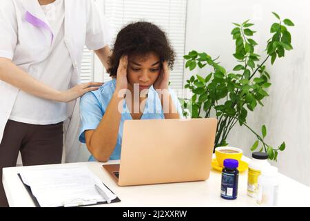 Weinend verärgert gemischte Rasse Krankenschwester oder afro amerikanischen Arzt mit Problemen mit Stress Zusammenbruch bei der Arbeit. Kollegen trösten sie. Stockfoto