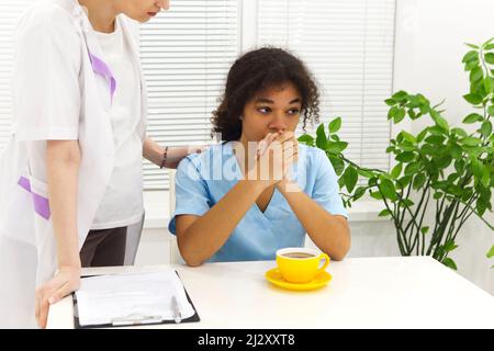 Weinend verärgert gemischte Rasse Krankenschwester oder afro amerikanischen Arzt mit Problemen mit Stress Zusammenbruch bei der Arbeit. Kollegen trösten sie. Stockfoto