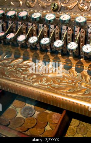 Altmodische Kasse. Detailreich auf den Schlüsseln und der Schublade eines aufwändig dekorierten Vintage-Shops, bis er mit alten englischen Münzen gefüllt ist. Stockfoto