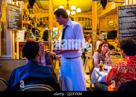 Paris, Frankreich, Französisches Bistro Restaurant, Le Petit Marcel, Les Halles, Französischer Kellner, der Gäste nachts auf der Terrasse bedient Stockfoto