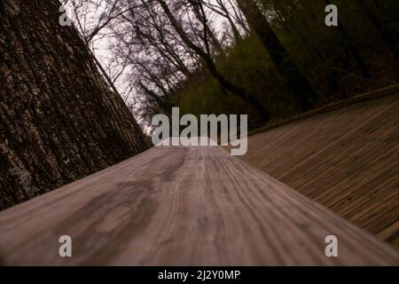 Blick auf eine lange und schmale Holzbrücke im Suwanee Town Center Park Stockfoto