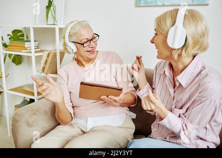 Porträt einer erwachsenen Tochter mit Mutter, die gemeinsam tanzt und Musik in Kopfhörern hört Stockfoto