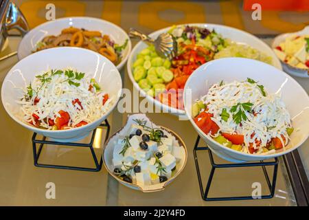 Griechischer Feta-Käse und gemischte Salate werden in Schüsseln am Buffet serviert Stockfoto