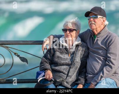 Glückliche, ältere Großeltern besuchen und sitzen auf einer Parkbank an den Niagara Falls in Brampton, Ontario, Kanada. Stockfoto