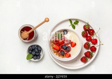 Gesundes Frühstück mit Müsli, Joghurt und frischen Beeren in einer weißen Schüssel. Blick von oben Stockfoto
