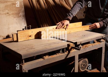 Zimmermann schleift Holzplatte auf einer Schleifmaschine. Stockfoto