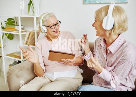 Porträt einer erwachsenen Tochter mit Mutter, die gemeinsam tanzt und Musik in Kopfhörern hört Stockfoto
