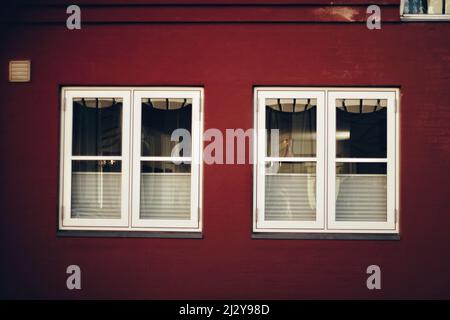 Die beiden Fenster an der leuchtend roten Wand. Stockfoto