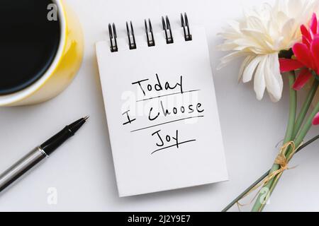 Notizbuch mit inspirierenden Zitate mit Blumendekoration und Kaffeebecher. Heute wähle ich Freude. Stockfoto