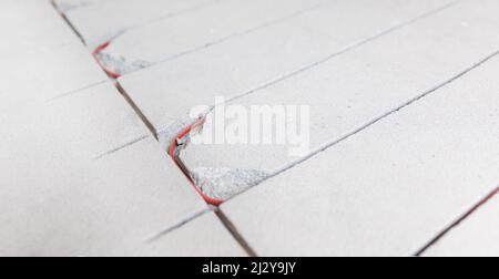 Stroboskopleitung in Zementestrich zum Verlegen von rotem Elektrokabel für Fußbodenheizung. Stockfoto