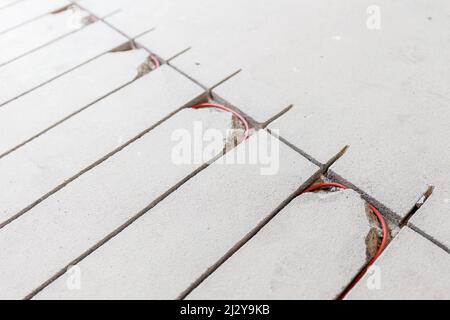 Stroboskopleitung in Zementestrich zum Verlegen von rotem Elektrokabel für Fußbodenheizung. Stockfoto