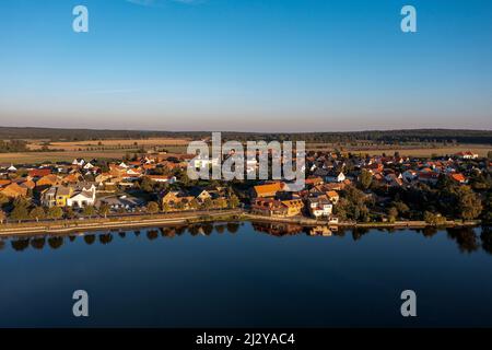 Laubbäume und Häuser spiegeln sich im Burgteich Flechtingen, Sachsen-Anhalt, Deutschland Stockfoto