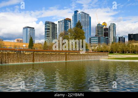 Bellevue, WA, USA - 31. März 2022; Wasserfall im Downtown Park in Bellevue vor der modernen Skyline der Stadt und geschwollenen Wolken im Frühling Stockfoto