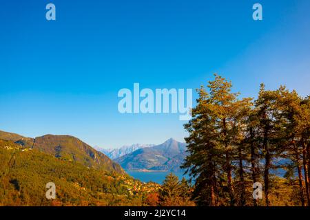 Panoramablick über das Dorf Menaggio mit alpinem Comer See mit Berg an einem sonnigen Herbsttag in der Lombardei, Italien. Stockfoto