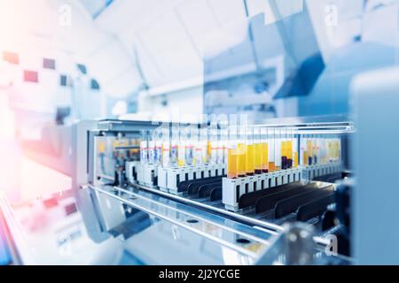 Wissenschaftler, die mit einer automatischen Robotermaschine zur Blutuntersuchung arbeiten, moderne medizinische Laborgeräte. Stockfoto