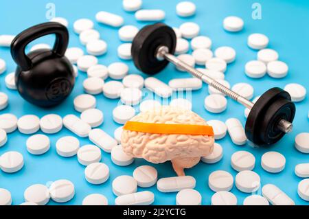 Pharmazeutische Ergänzung für psychische Fitness, Gesundheit des Geistes und nootrischer Medikamente Konzept mit menschlichem Gehirn mit Stirnband, Langhantel, Kettlebell und Noototropi Stockfoto