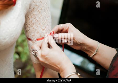 Mutter Frau, die ein Band auf das Brautkleid bindet Stockfoto