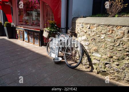 Traditionelle Metzgerei mit Metzgerfahrrad draußen und Tafeln mit Schaufenster. Seaton, Devon, Großbritannien (Mar22) Stockfoto