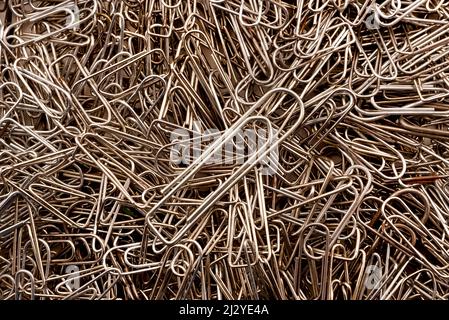 Hintergrund von Büroklammern in Stahlfarbe. Die Heftklammern sind zufällig über die Oberfläche verteilt. Stockfoto