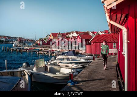 Frau am Hafen im Dorf Kyrkesund auf der Schäreninsel Tjörn an der Westküste Schwedens, blauer Himmel mit Sonne Stockfoto