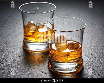 Zwei Gläser eleganter Whiskey mit Eis auf schwarzem strukturiertem Hintergrund. Konzept für harte Getränke. Stockfoto