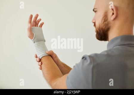 Der Mensch verwendet medizinische Verbandsmaterial für das Handgelenk als vorbeugende Maßnahme für Sport oder körperliche Aktivität. Stockfoto