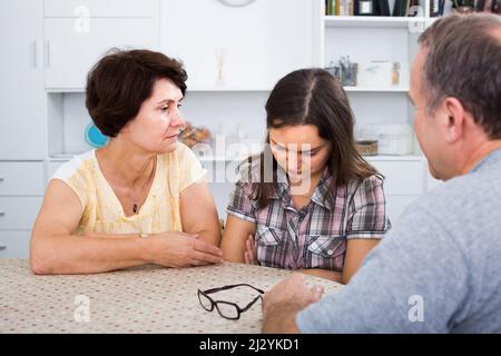 Frau schaut traurig, während sie mit älteren Eltern spricht Stockfoto