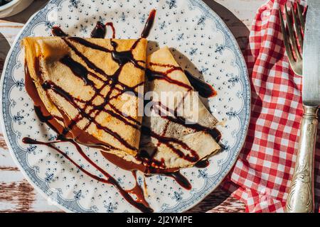 Teller zwei exquisite hausgemachte Pfannkuchen oder Crepes mit Mandelcreme und Schokolade mit Schokoladenfäden bedeckt gefüllt. Stockfoto