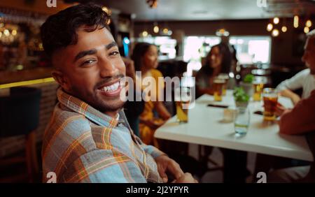 afrikanischer Ameirikaner lächelt, während er mit Freunden auf einen Drink ausgeht Stockfoto