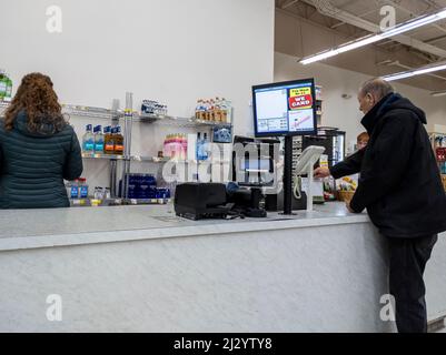 Gold Bar, WA USA - circa Januar 2022: Älterer Mann, der im Gold Bar Family Grocer eine Lotteriekarte kauft. Stockfoto