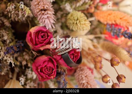 Diamant-Hochzeitsring mit Hochzeitsband und Blumenstrauß aus getrockneten Wildblumen Stockfoto