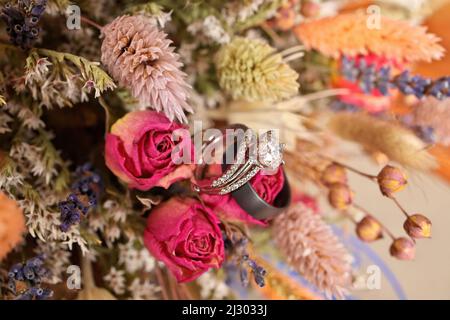 Diamant-Hochzeitsring mit Hochzeitsband und Blumenstrauß aus getrockneten Wildblumen Stockfoto