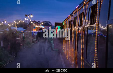 Passagiere, die das beleuchtete Weihnachtsangebot „Winterlichter“ auf der West Somerset Railway am Bahnhof Bishops Lydeard besteigen. Stockfoto