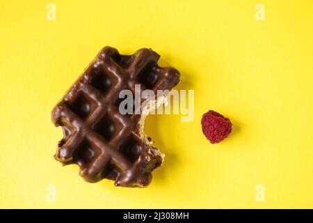 Von Schokoladenwaffel und Himbeere gebissen, gelber Hintergrund, Draufsicht. Stockfoto