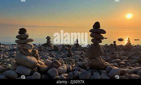 Viele Stapel von Kieselsteinen am Strand während des Sonnenuntergangs Stockfoto