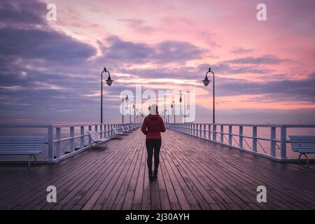 Stimmungsvolles Meereskonzept mit einer Frau. Mädchen auf einem hölzernen Pier in Gdynia, Polen. Stockfoto