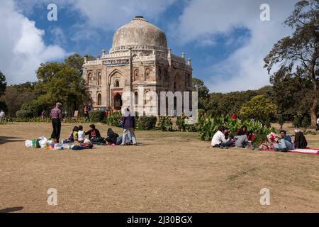 Neu-Delhi, Indien. Lodi Gardens. Indische Familien, die an einem Samstagnachmittag vor Sheesh Gumbad ein Picknick machen. Stockfoto
