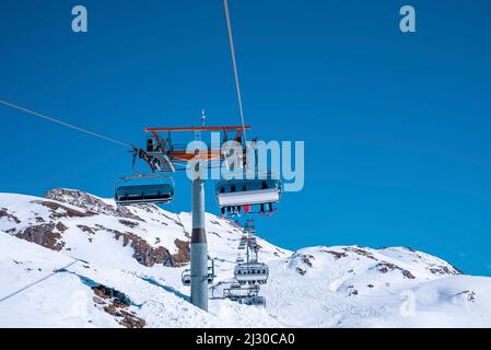 Seilbahnen fahren über schneebedeckten Berghang gegen klaren blauen Himmel Stockfoto