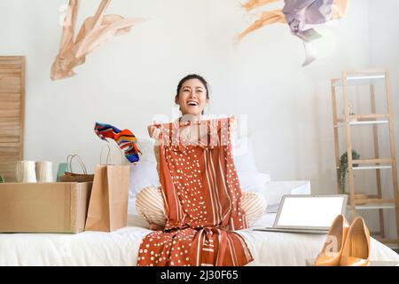 Glückliche junge Frau mit neuem Kleid zu Hause. Online-Shopping Stockfoto