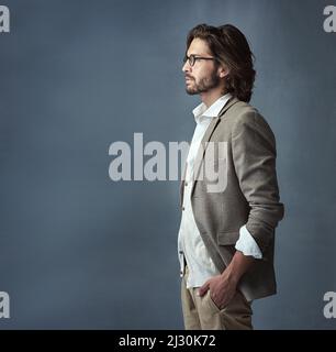 Hes ein Mann der Klasse. Beschnittene Studioaufnahme eines hübschen und stilvollen jungen Mannes vor grauem Hintergrund. Stockfoto