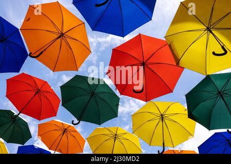 Bunte Regenschirme hängen am blauen Himmel. Stadtkunst Stockfoto