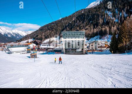 Skifahrer Skifahren in Richtung Bahnhof auf verschneiten Berg in den alpen mit dichtem Wald Stockfoto