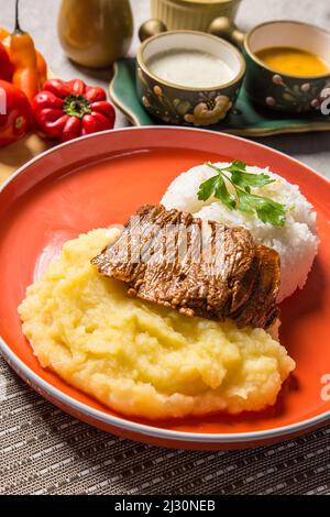 Hühnchen- oder Rinderfleisch mit Kartoffelpüree peruanisches Komfortessen hausgemachte traditionelle Gastronomie Buffettisch Stockfoto