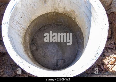 Installation eines Drehrohrs eines Kanals mit freiem Durchfluss für Entwässerung, Sturm- oder Abwasser zur Ableitung von Abwasser in die Hauptabwasserkanalleitung, selektiver Fokus Stockfoto