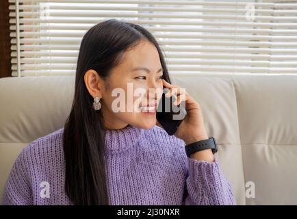 Asiatisches Mädchen mit Brille, Kopfhörer und Pflanzen, die von zu Hause aus mit einem Laptop und Handy arbeiten. Stockfoto