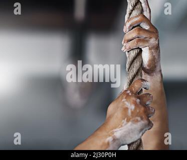 Hol dir den Griff. Kurzer Schuss eines jungen Mannes, der im Fitnessstudio ein Seil klettert. Stockfoto