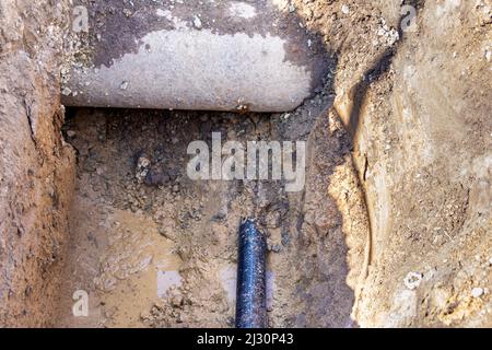 Durchquerung unterirdischer Pipelines und Kommunikation in verschiedenen Tiefen am Boden des Grabens, selektiver Fokus Stockfoto