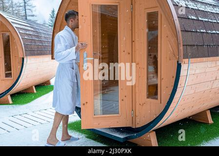 Mann im Bademantel beim Betreten des runden Badehauses während des Winterschneehauses Stockfoto